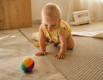 Baby chasing after a rainbow ball