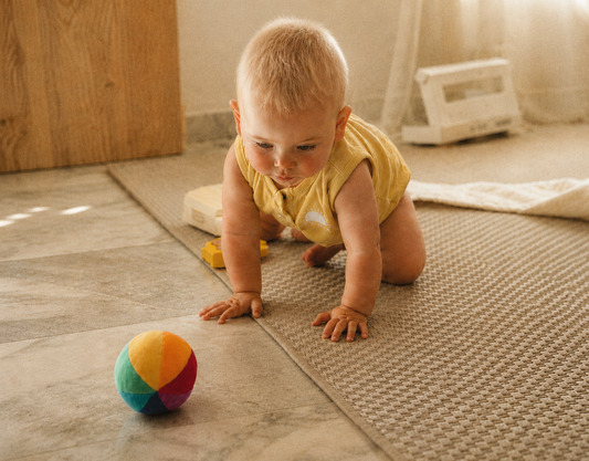 Baby chasing after a rainbow ball