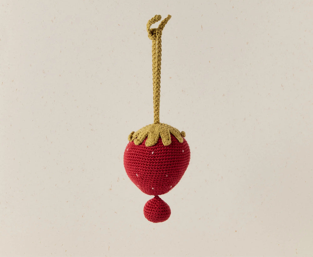 Crocheted strawberry ornament with a yellow stem on a beige background