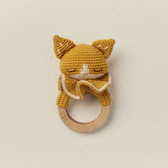 Crocheted cat rattle on a wooden ring with a plain background