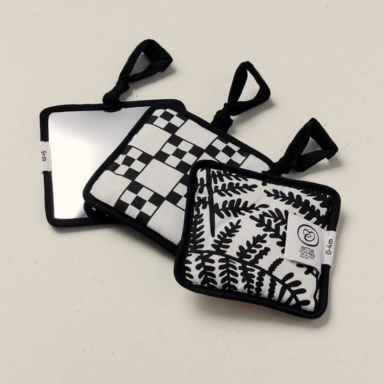 Three black and white patterned sensory squares on a beige background