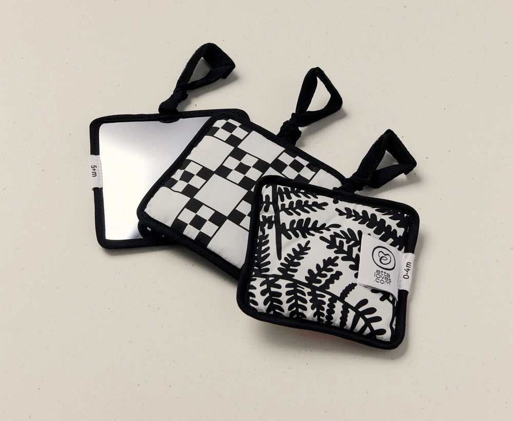 Three black and white patterned sensory squares on a beige background