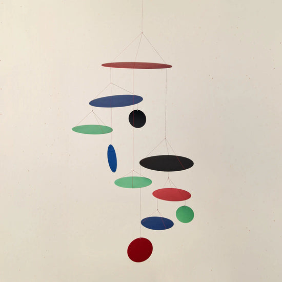 Colorful hanging mobile with circular shapes on a plain background