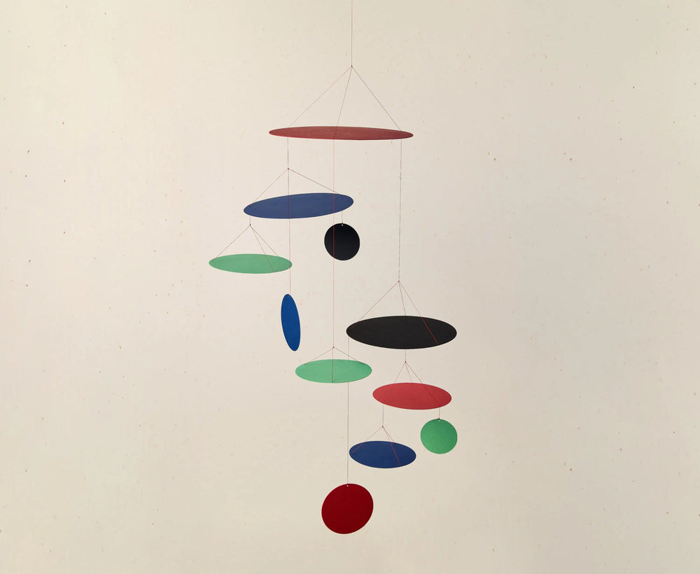 Colorful hanging mobile with circular shapes on a plain background
