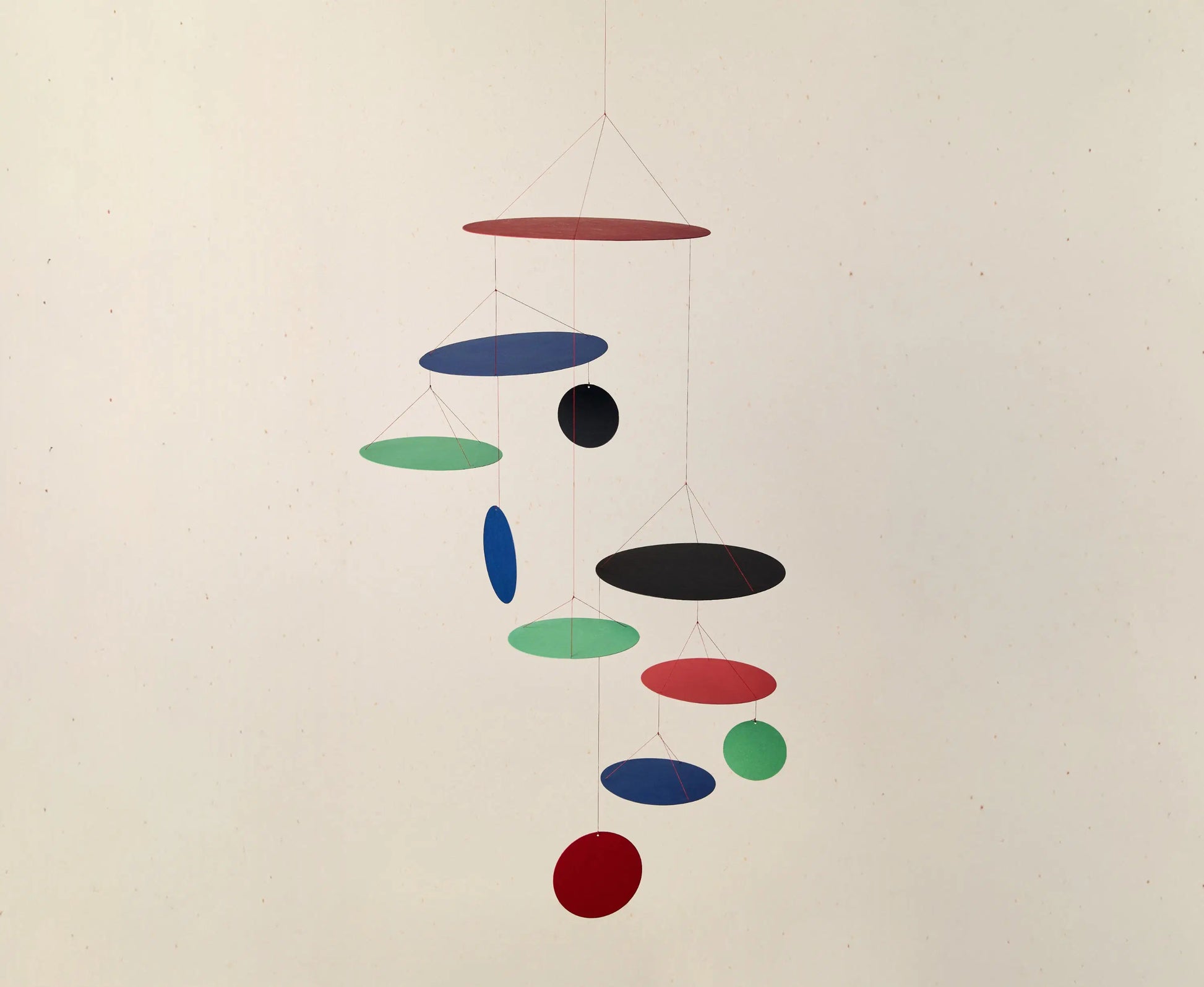 Colorful hanging mobile with circular shapes on a plain background