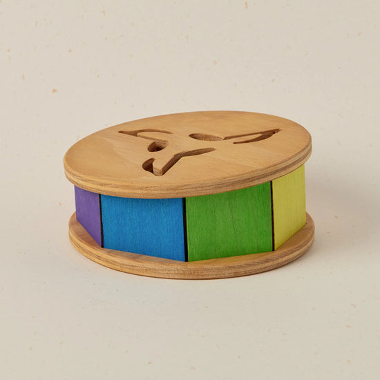 Wooden toy with colorful cylindrical sections on a beige background