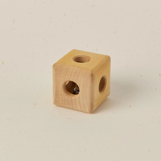 Wooden cube with two circular holes on a beige background