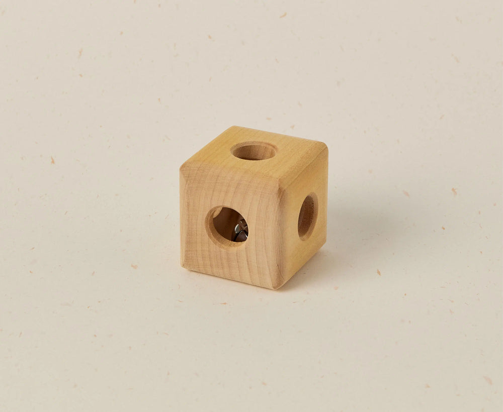 Wooden cube with two circular holes on a beige background