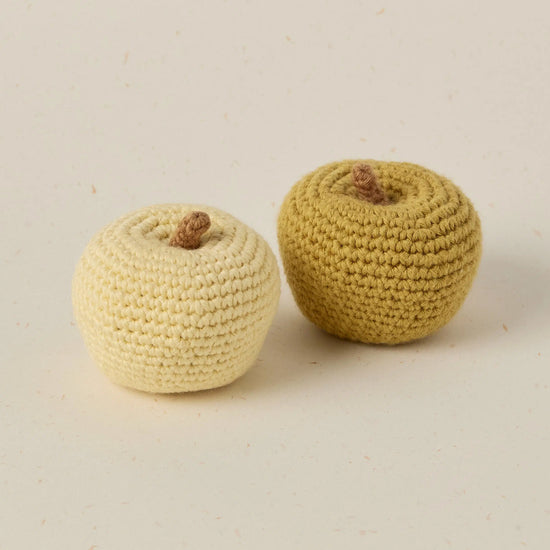 Two crocheted apples on a beige background