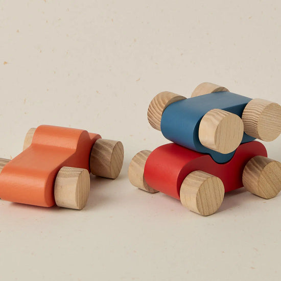 Two wooden toy cars in red and blue on a beige background