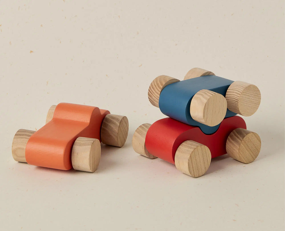 Two wooden toy cars in red and blue on a beige background