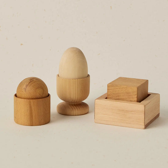Set of wooden egg cups and a wooden block on a beige background