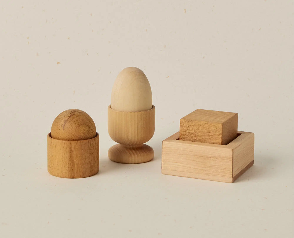 Set of wooden egg cups and a wooden block on a beige background