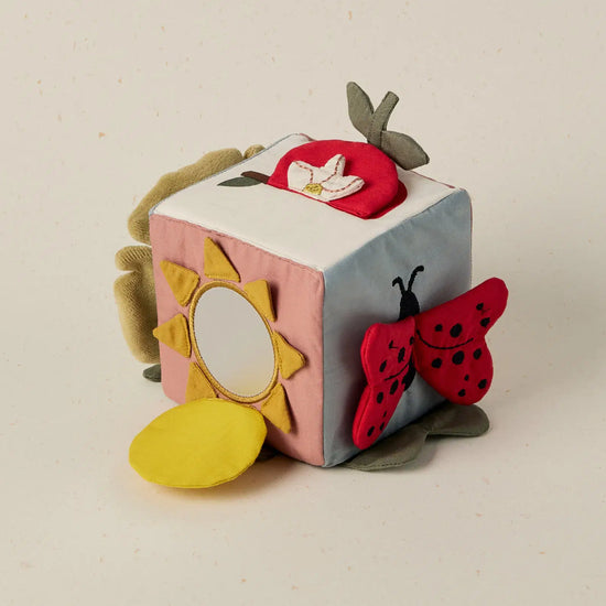 Children's soft activity cube with animal and nature-themed designs on a beige background