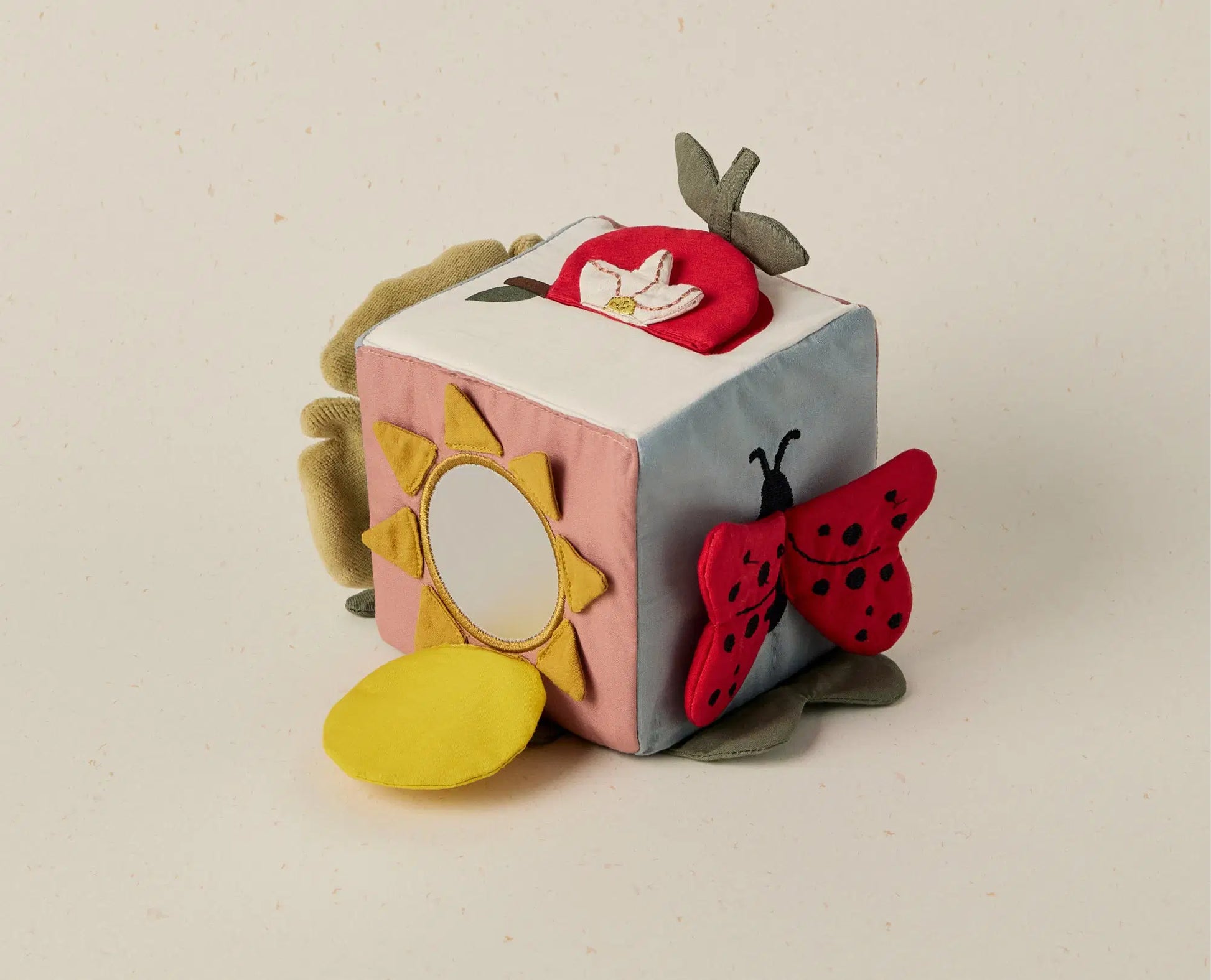 Children's soft activity cube with animal and nature-themed designs on a beige background