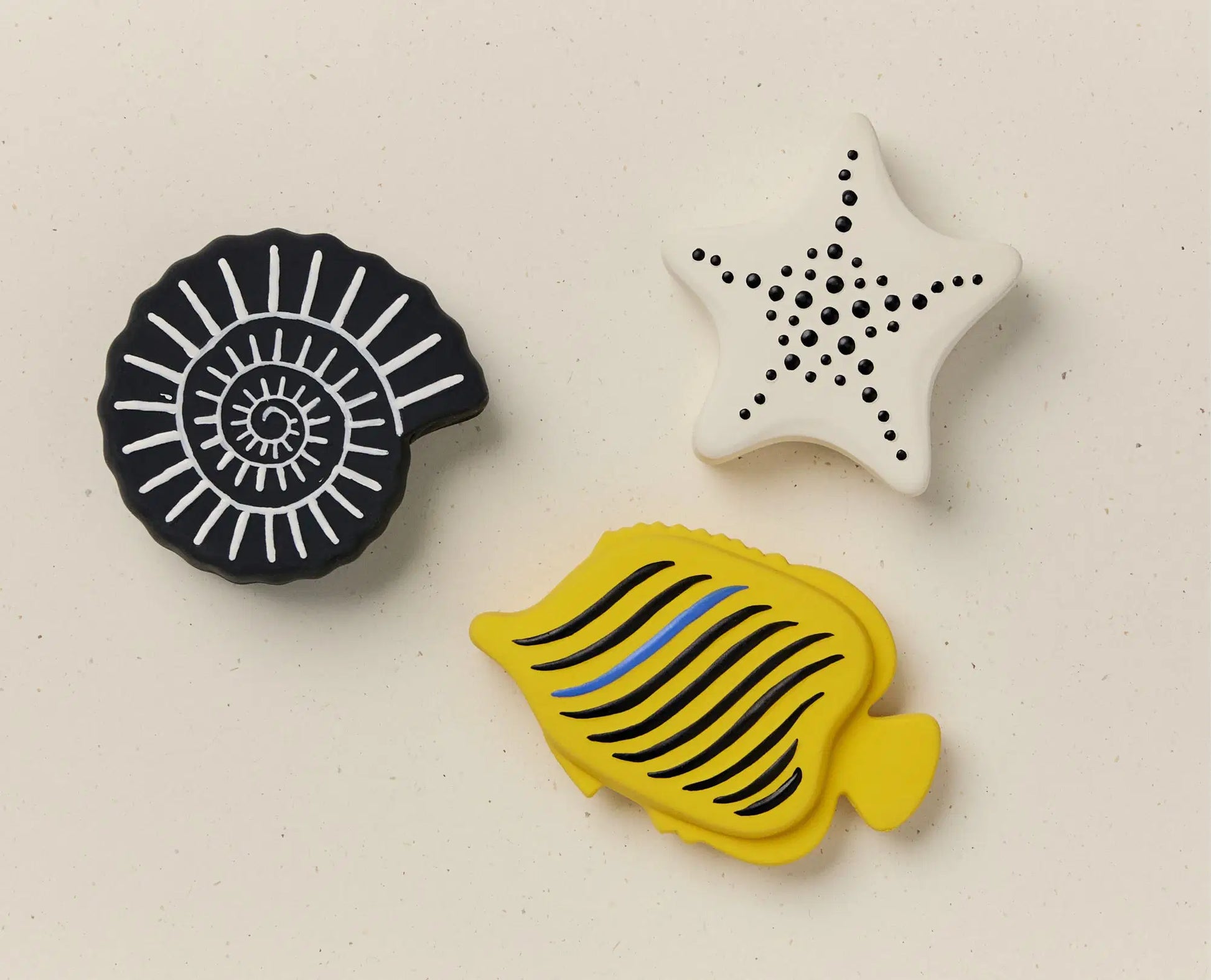 Three bath toys with geometric patterns on a beige background