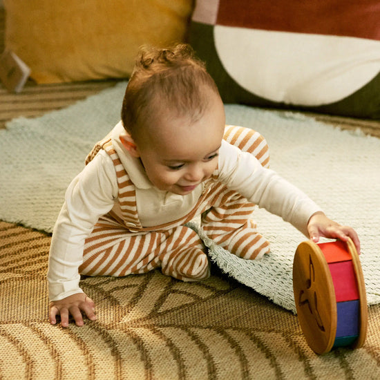 Baby playing with a colorful toy on a patterned rug