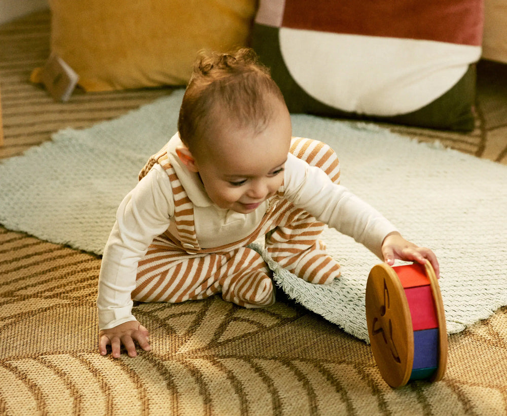 Baby playing with a colorful toy on a patterned rug