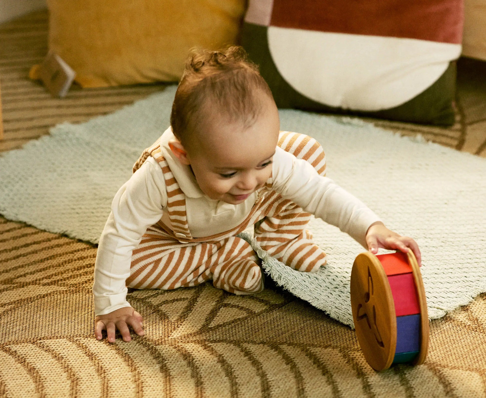 Baby playing with a colorful toy on a patterned rug