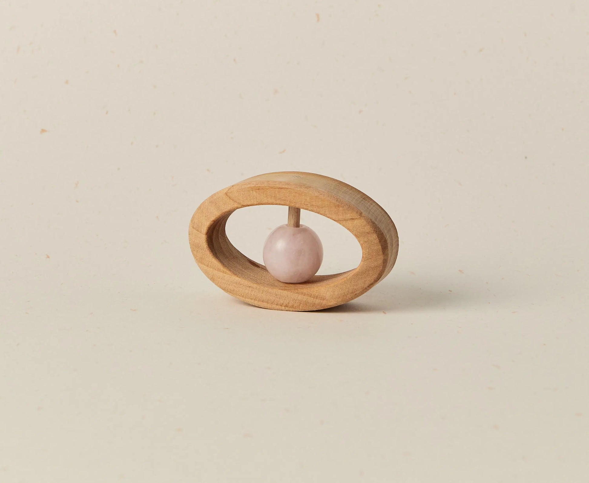 Wooden baby teether with a pink stone on a beige background