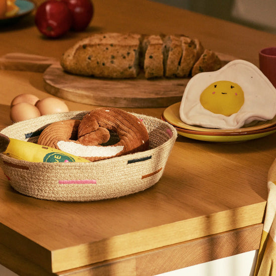 Wooden table with bread, eggs, and a smiley face egg on a plate.