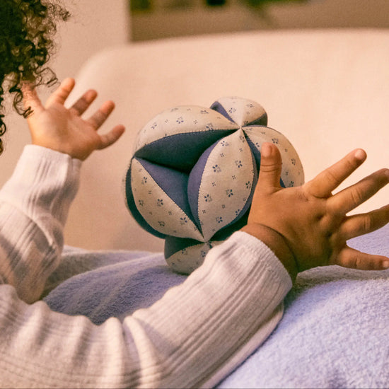 Child playing with a patterned ball on a soft surface