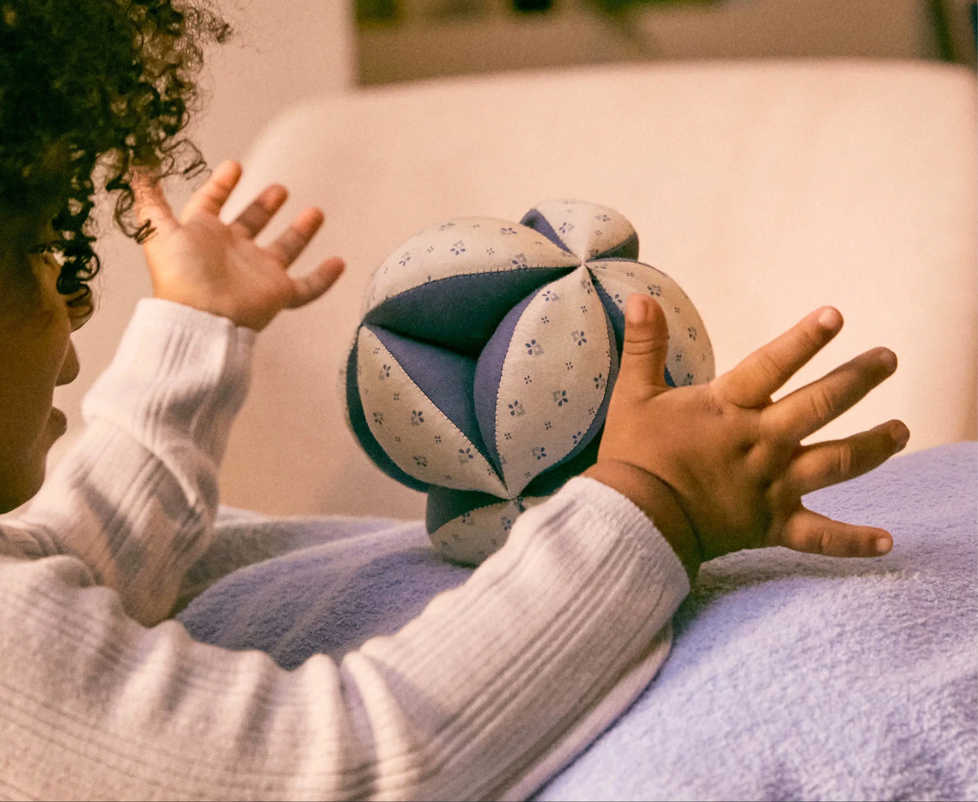 Child playing with a patterned ball on a soft surface