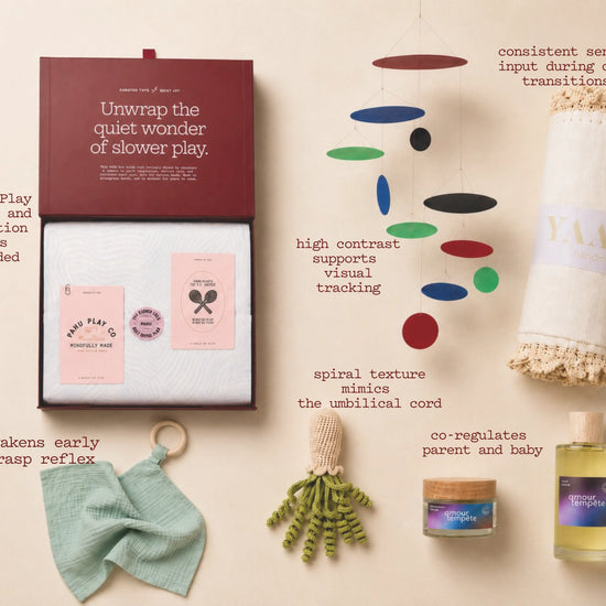 Collection of baby products including cards, toys, and a oil bottle on a beige background