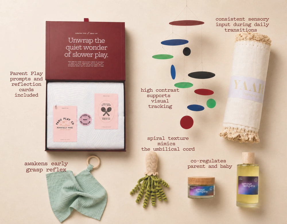 Collection of baby products including cards, toys, and a oil bottle on a beige background